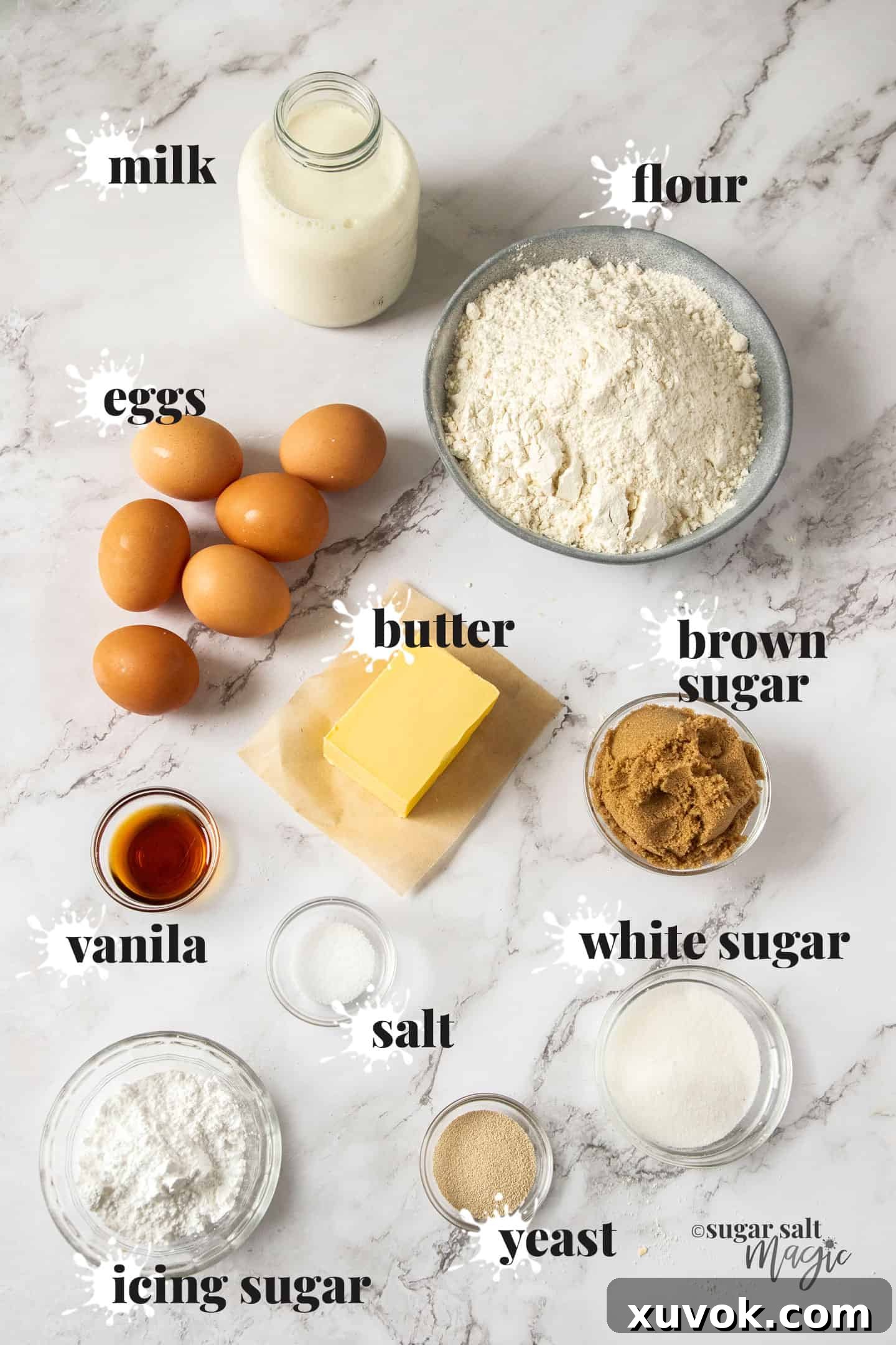 Ingredients for fluffy caramel doughnuts on a marble benchtop, including flour, milk, eggs, sugar, butter, and yeast.