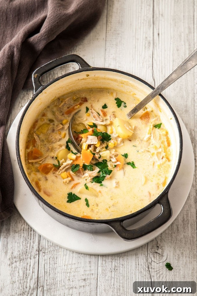 A top-down view of a large pot filled with a rich, creamy turkey corn chowder, ready to be served.