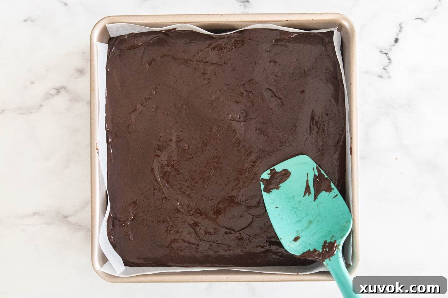 The freshly made dark chocolate fudge mixture poured into a parchment-lined baking pan, ready for chilling and setting.