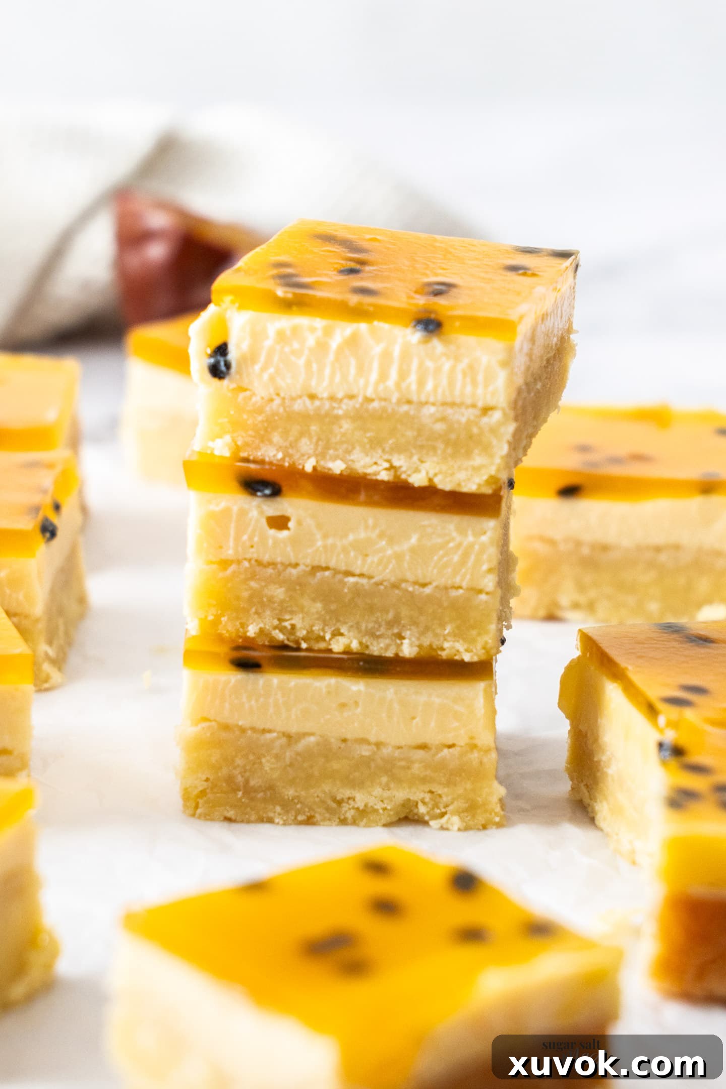 A stack of three perfectly cut passionfruit bars, showcasing their distinct layers.