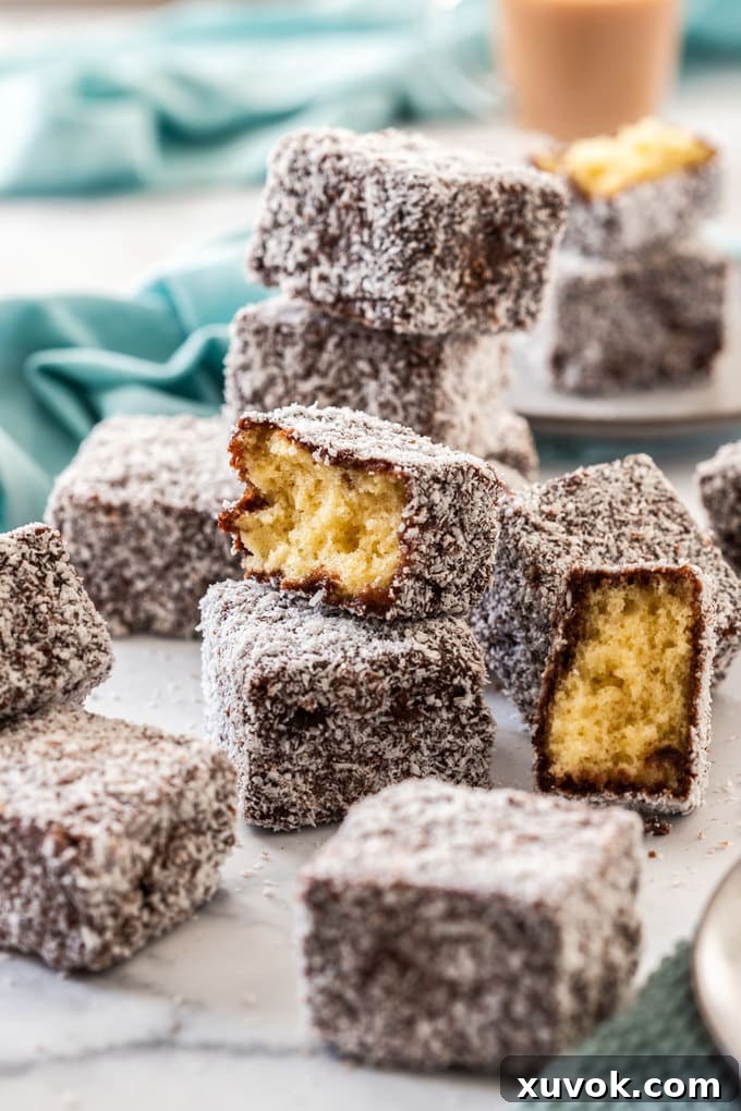 A pile of lamingtons with one broken in half and a turquoise napkin in the background.