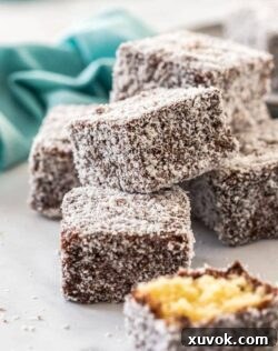 A pile of lamingtons with one broken in half and a turquoise napkin in the background.