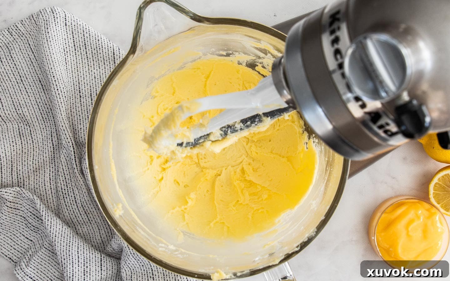 Softened butter and powdered sugar expertly beaten together in a large stand mixer bowl, forming a pale, creamy and airy mixture, ready for the next step of cookie dough preparation.