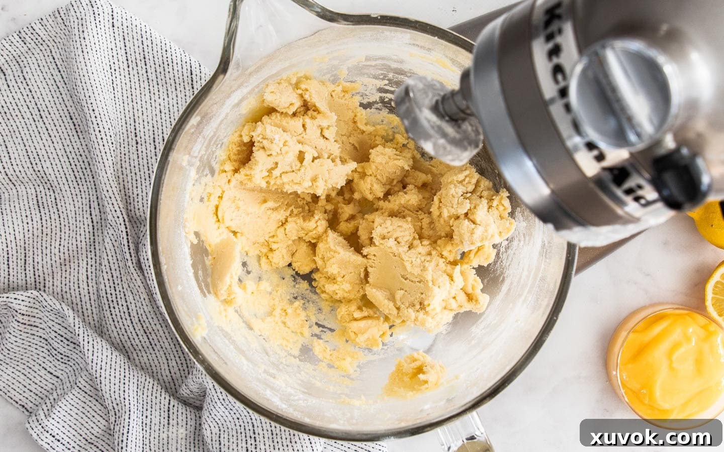 The perfectly mixed, soft, and pliable cookie dough resting in the bowl of a stand mixer, showcasing its readiness for shaping into delicious lemon curd cookies.