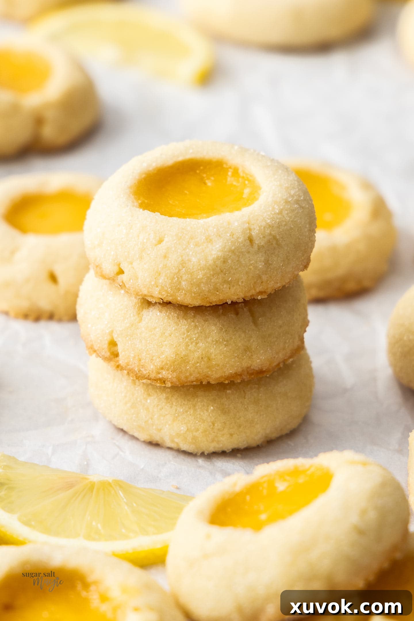 A beautifully arranged stack of three golden lemon curd thumbprint cookies, showing off their distinct centers, crumbly texture, and inviting appearance.