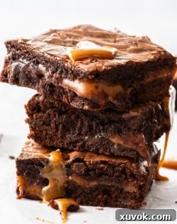 A stack of 3 brownies with caramel oozing down the sides.