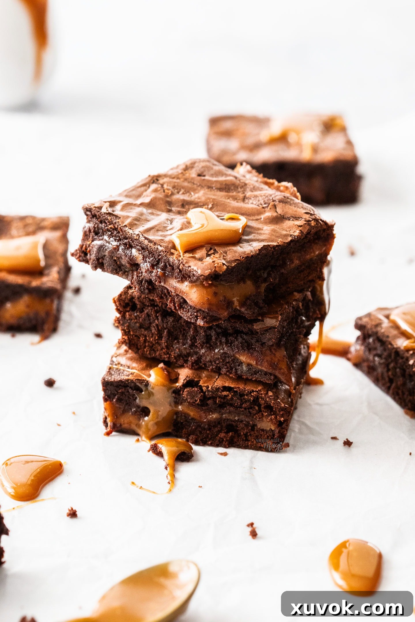A stack of 3 chocolate caramel brownies with golden caramel oozing down the sides.