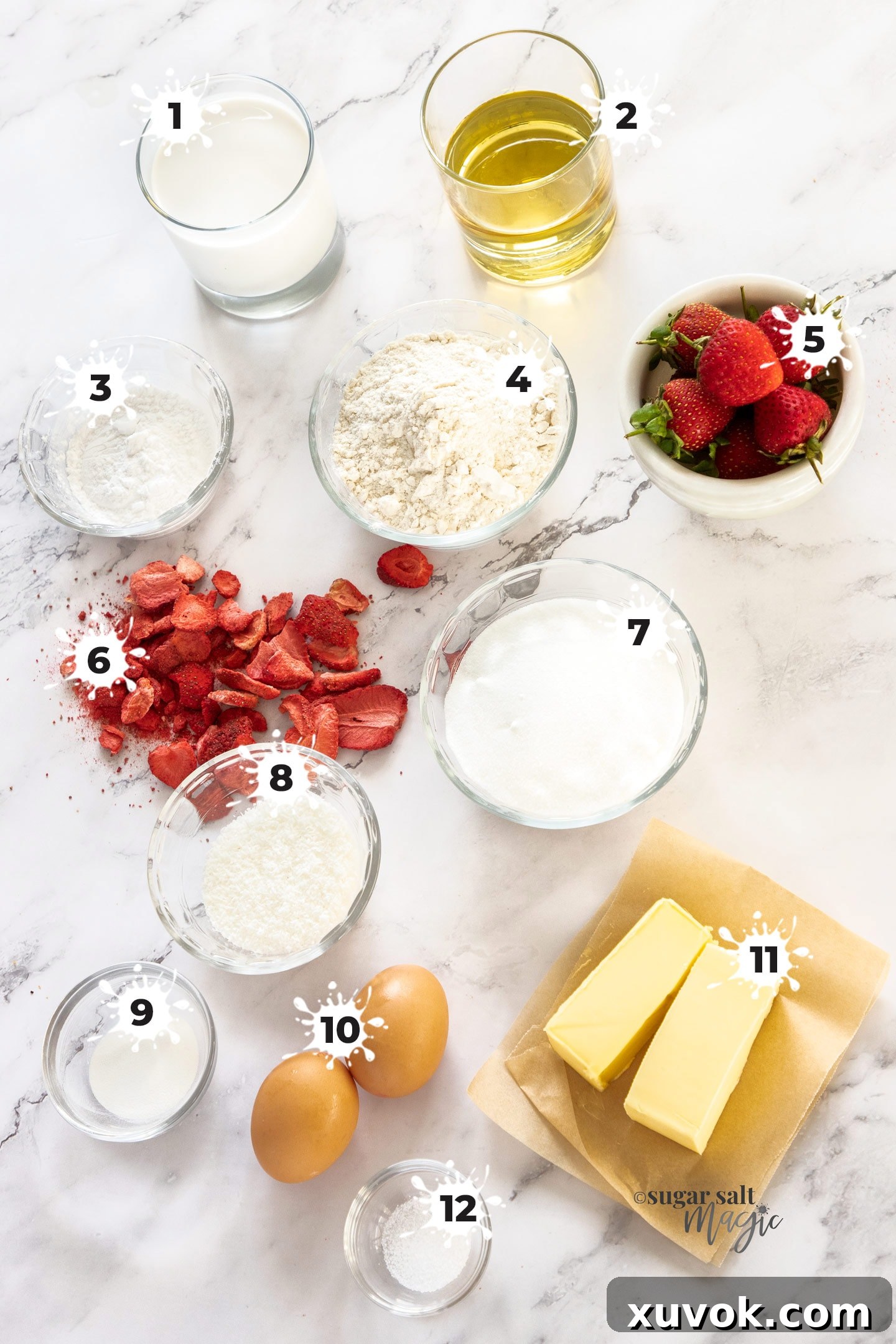 Ingredients for strawberry cheesecake cupcakes on a marble bench top, including coconut milk, desiccated coconut, cornflour, freeze-dried and fresh strawberries, and other baking essentials.
