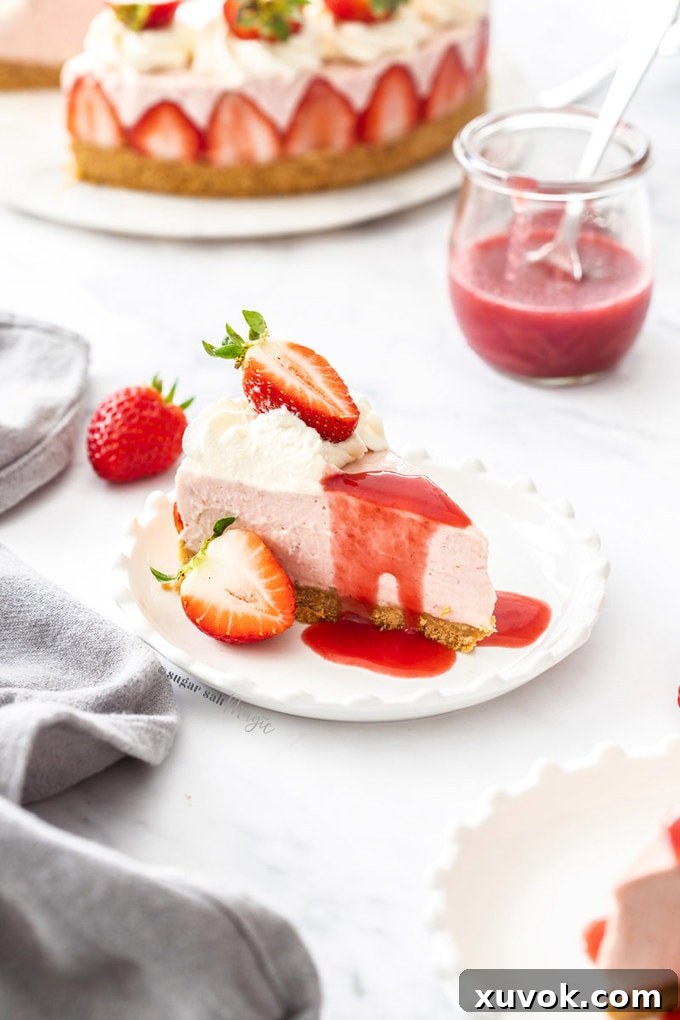 A slice of strawberry cheesecake with strawberry sauce, whipped cream and fresh berries, on a white plate