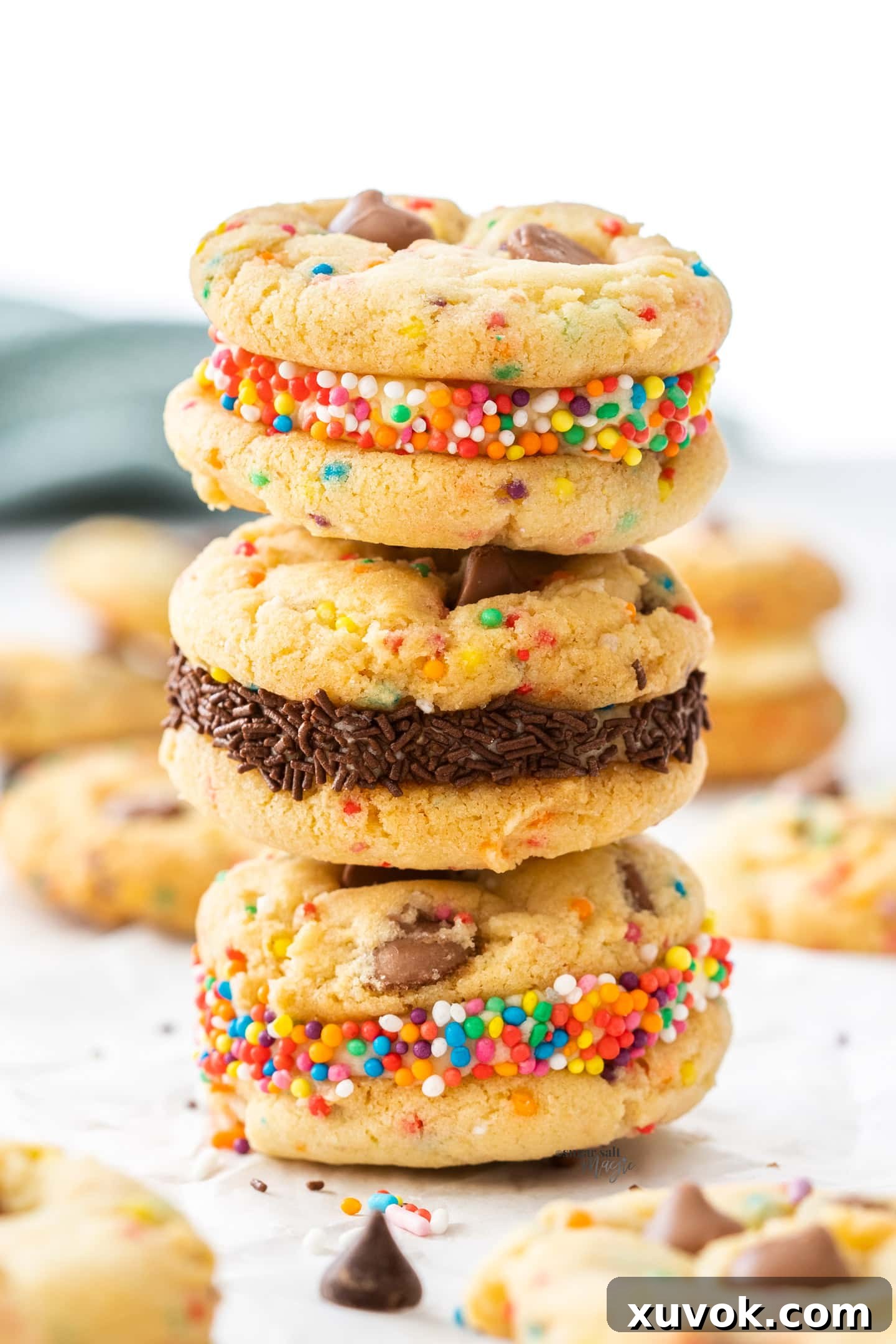 A stack of 3 buttercream-filled birthday cake cookies, adorned with colorful sprinkles.