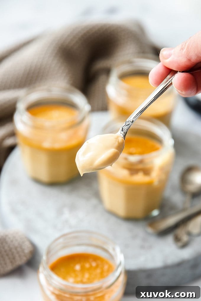 A close-up shot of a spoon generously loaded with smooth, glistening salted caramel custard, highlighting its creamy texture and inviting appearance. The perfect balance of sweet and salty is evident in every bite.