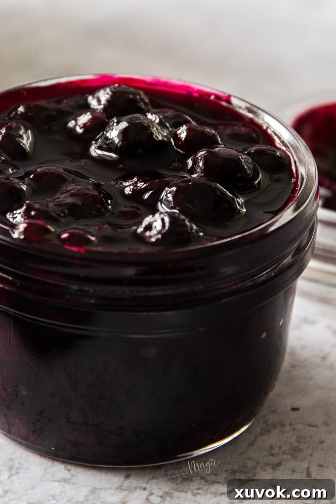 A small glass jar, filled to the brim with homemade blueberry pie filling.