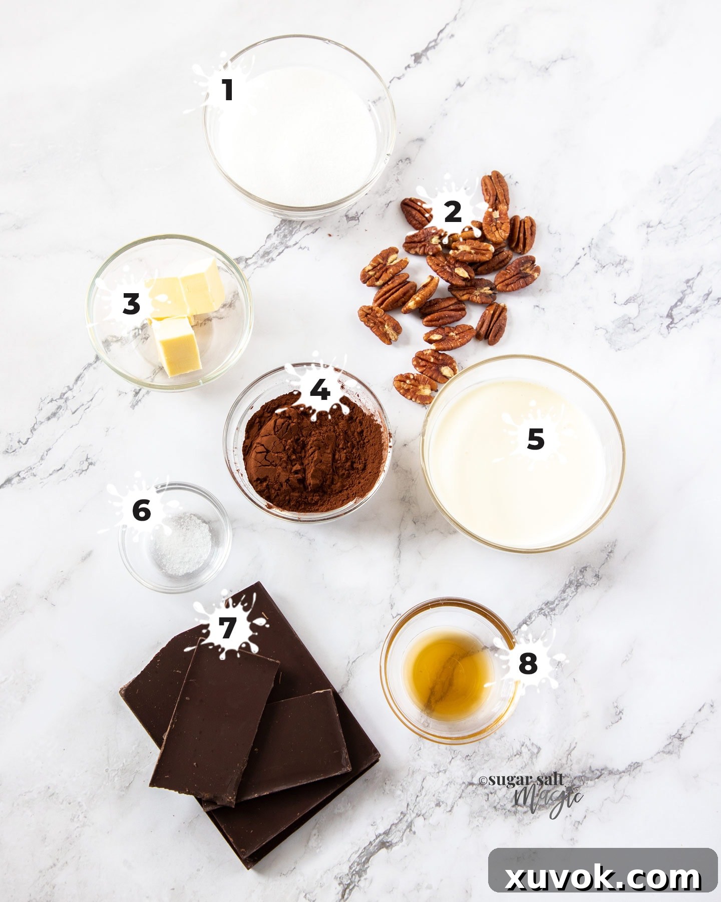 A flat lay photograph showcasing the simple yet essential ingredients for Toffee Pecan Chocolate Truffles: sugar, water, pecans, vanilla, salt, dark chocolate, heavy cream, and butter.