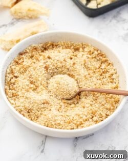 A white bowl filled with breadcrumbs with a spoon in it