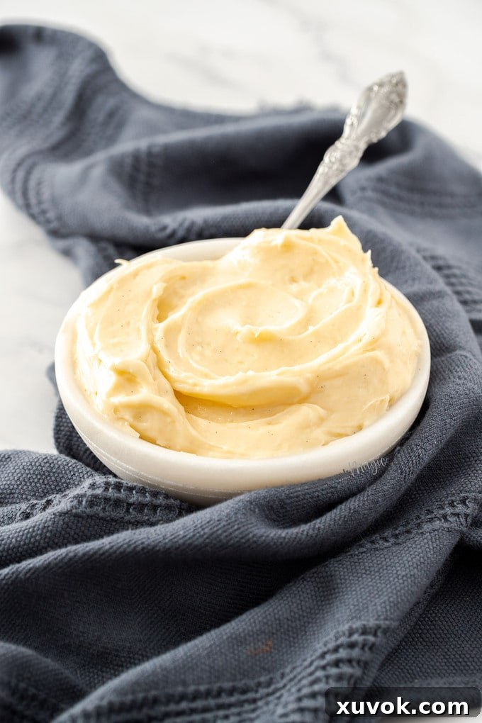 A glass bowl of vanilla pastry cream wrapped in a tea towel, ready for storage or chilling.