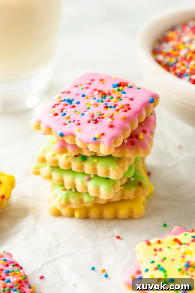A vibrant stack of colorful iced sugar cookies, generously coated in sprinkles.
