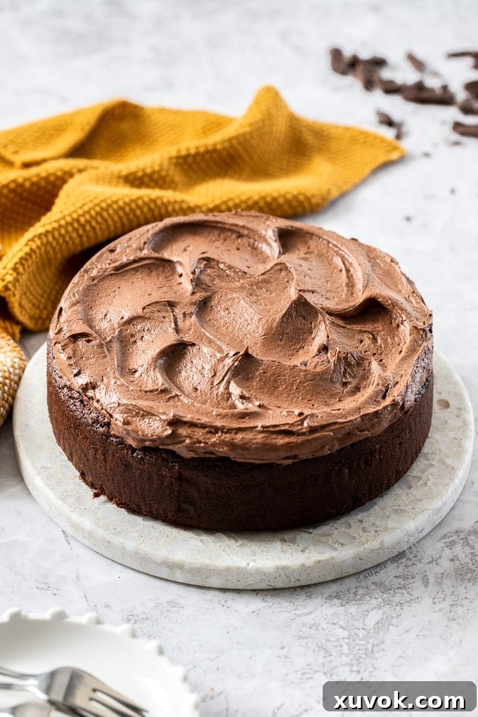 A chocolate mud cake on a marble platter. mustard coloured napkin in the background.