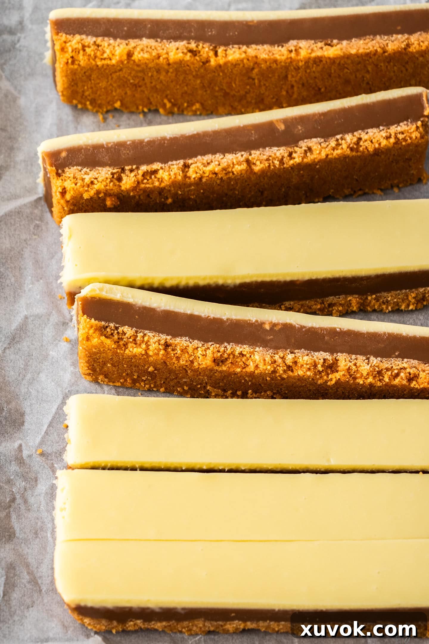 Slices of peanut butter caramel slice, showcasing layers of crunchy biscuit base, smooth caramel, and creamy white chocolate.