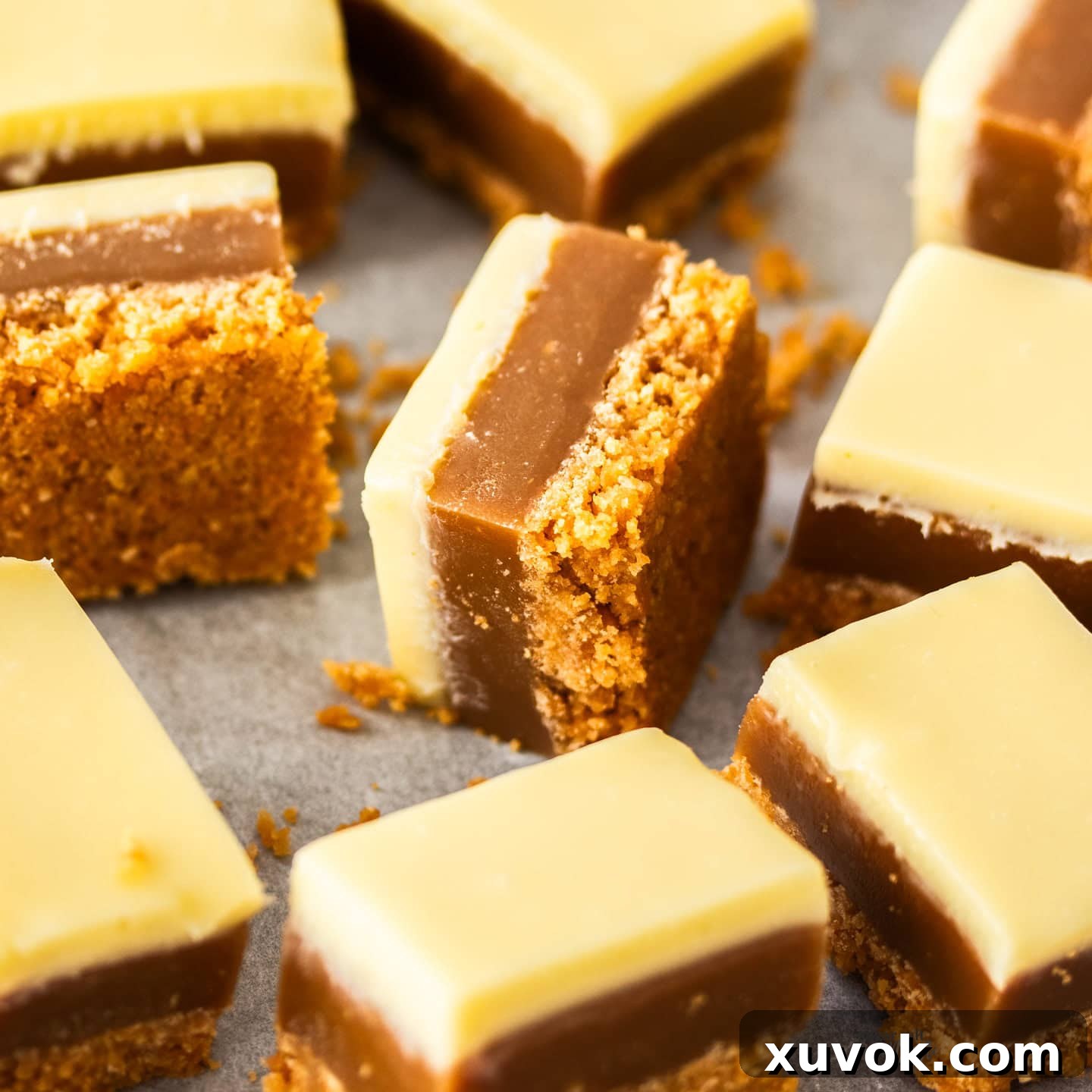 Closeup of a square of peanut caramel slice showing the distinct layers of base, caramel, and white chocolate.