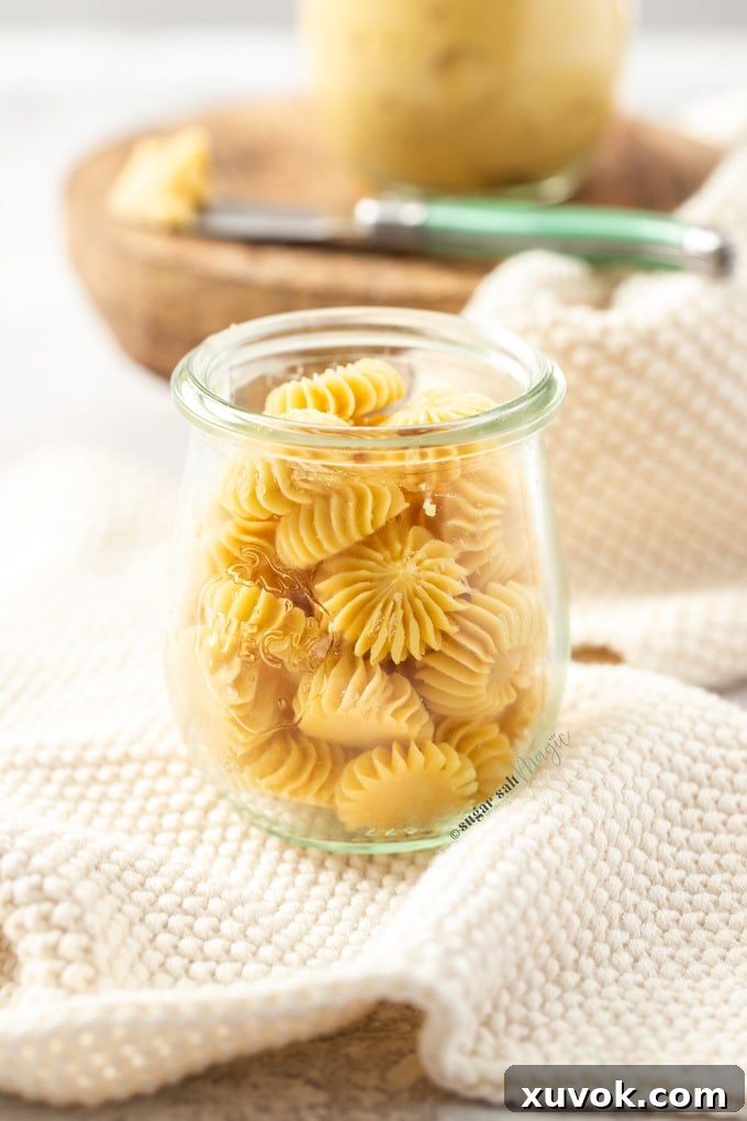 A small glass jar filled with pats of star shaped maple butter on a white crocheted napkin, showcasing the creamy texture and inviting presentation.