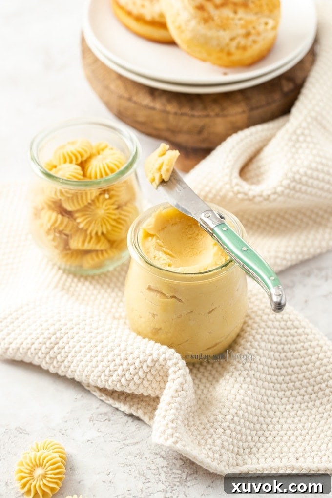 Two elegant pots of homemade whipped maple butter, one with a green butter knife, sitting on delicate white crocheted napkins, identical to the previous image, highlighting its inviting appeal and versatility.