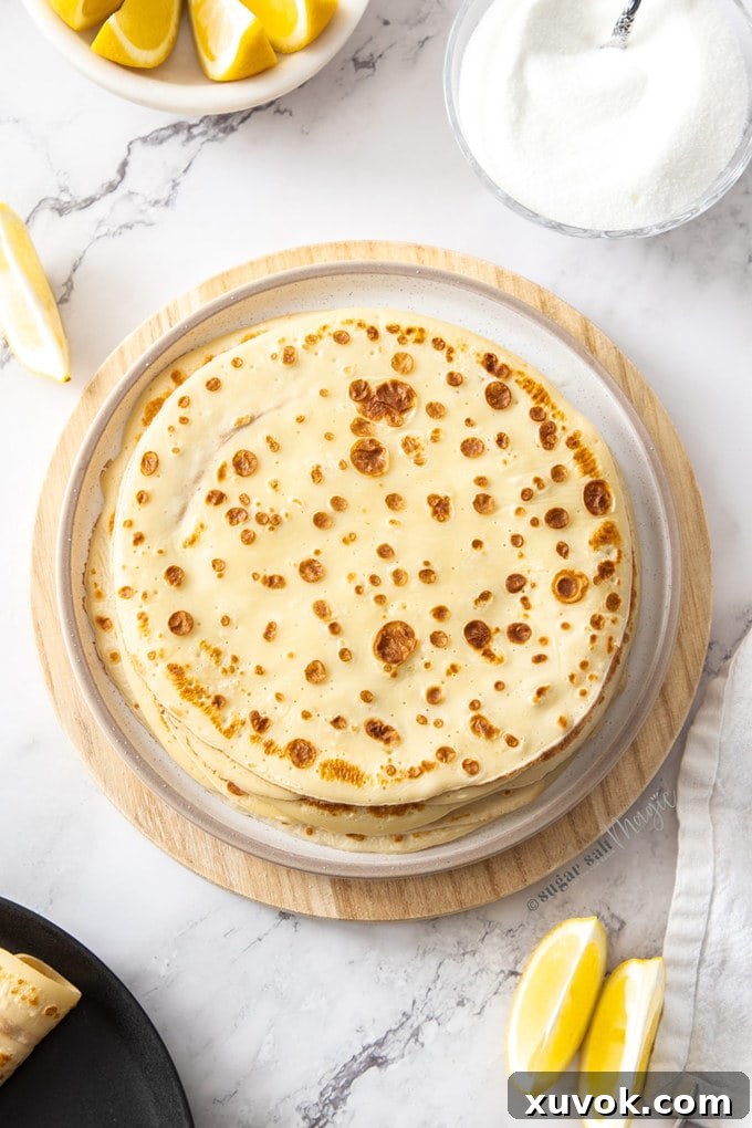 A white plate topped with a stack of english pancakes. 