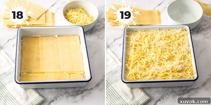 A white baking pan filled with assembled lasagna layers, topped with an even sprinkle of grated cheese, ready for baking.