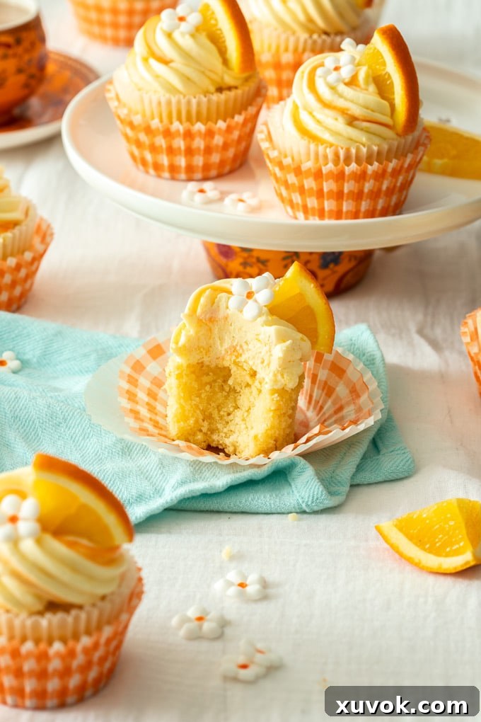 An orange cupcake cut open to reveal the fluffy texture, sitting on an aqua tea towel, showcasing its perfect crumb.