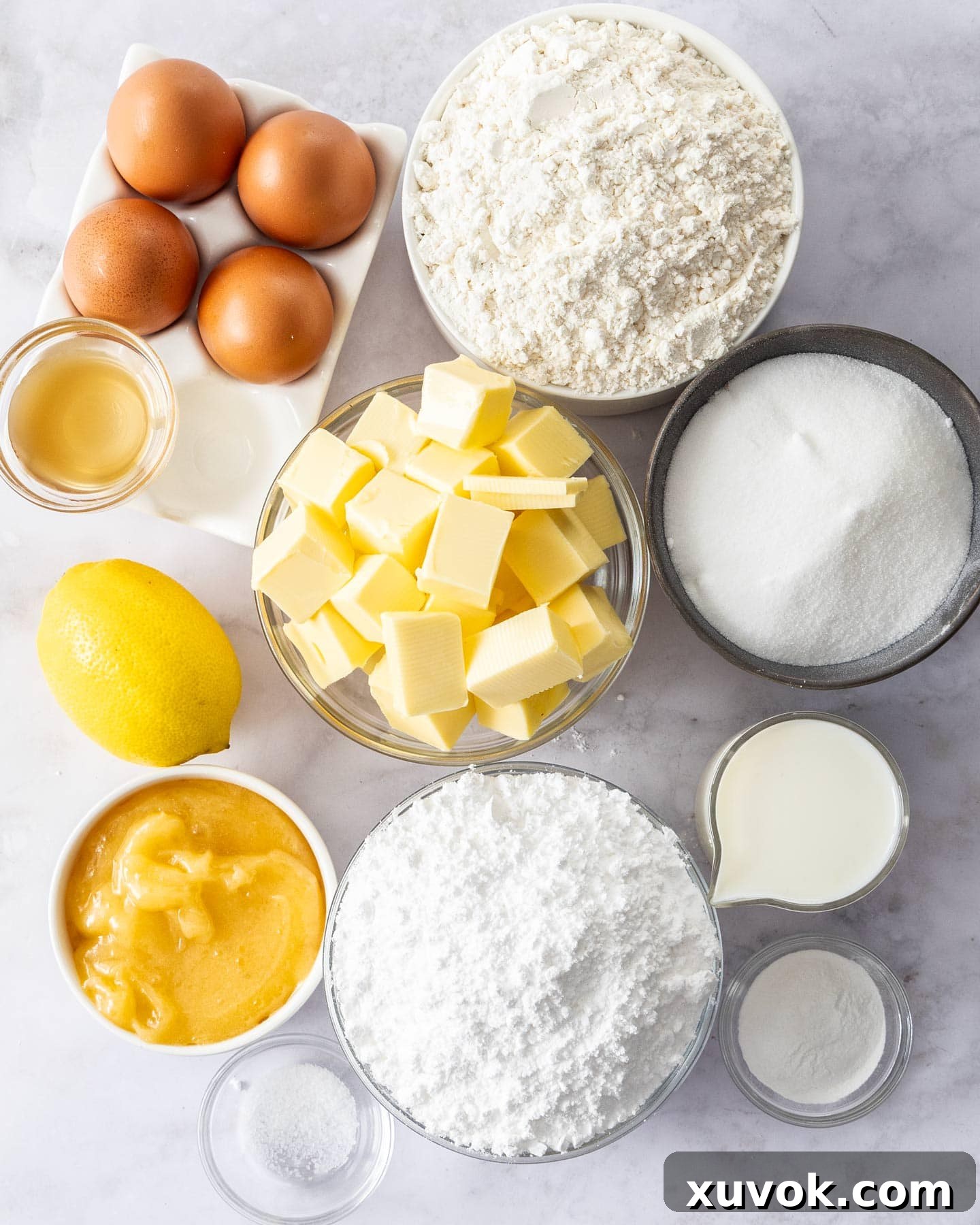 Ingredients for lemon butter cake artfully arranged on a marble surface, ready for baking.