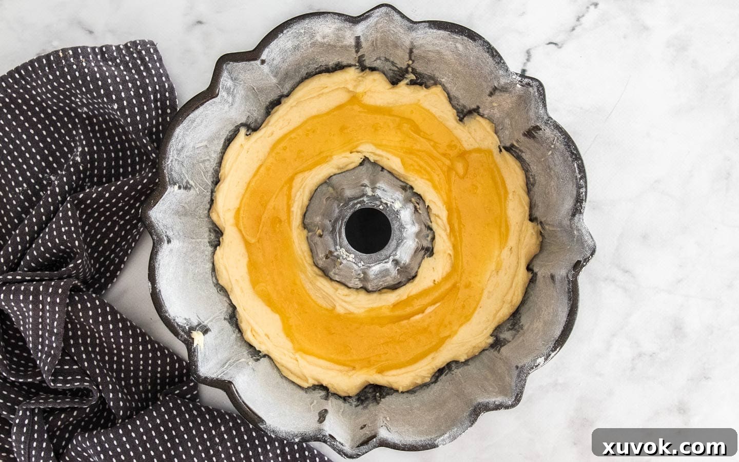 The bundt pan with distinct layers of cake batter and bright yellow lemon curd.