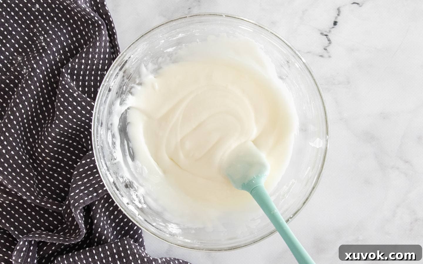 A glass bowl filled with smooth, vibrant lemon icing, ready to be drizzled over the cake.