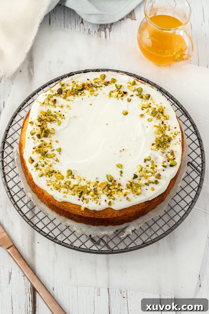 Top down view of a cake covered with yoghurt on a round rack.