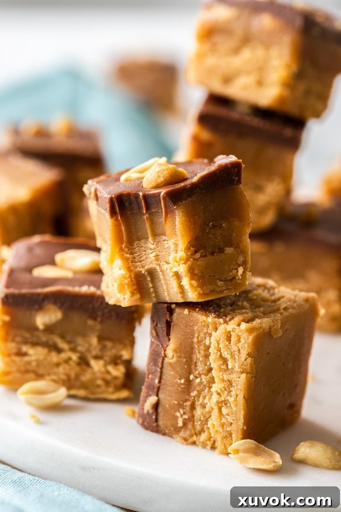 Pieces of caramel peanut fudge stacked up on a white platter. One with a bite taken out of it