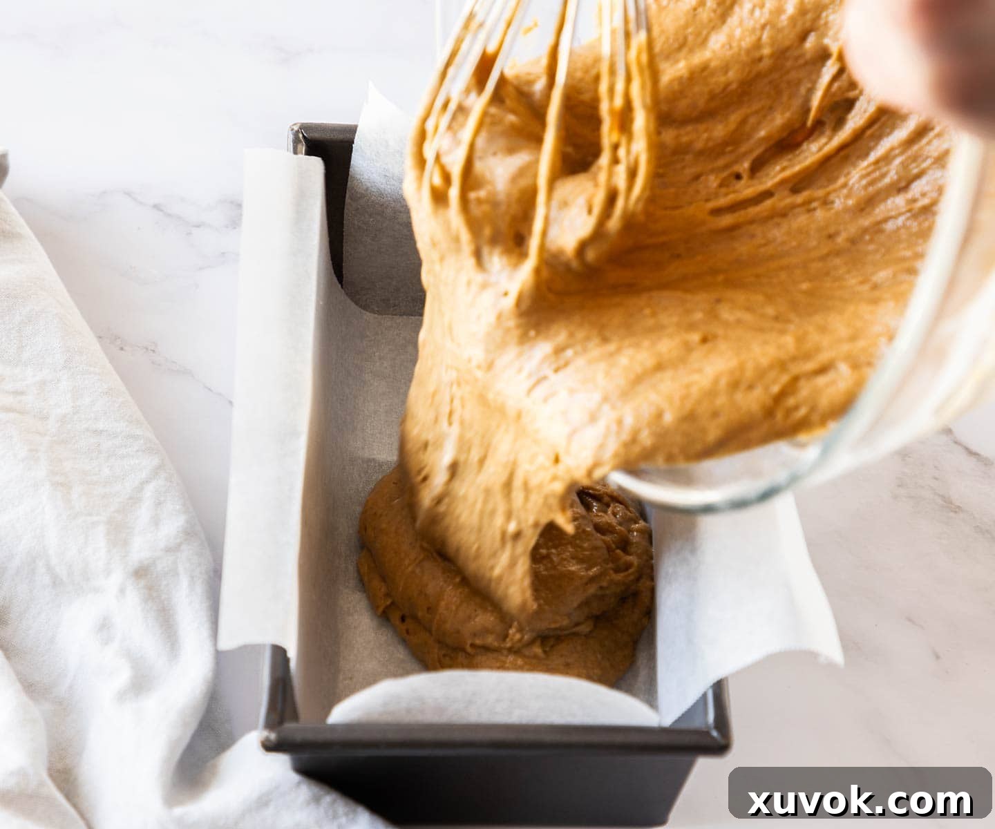 The ginger cake batter being poured into a loaf pan.