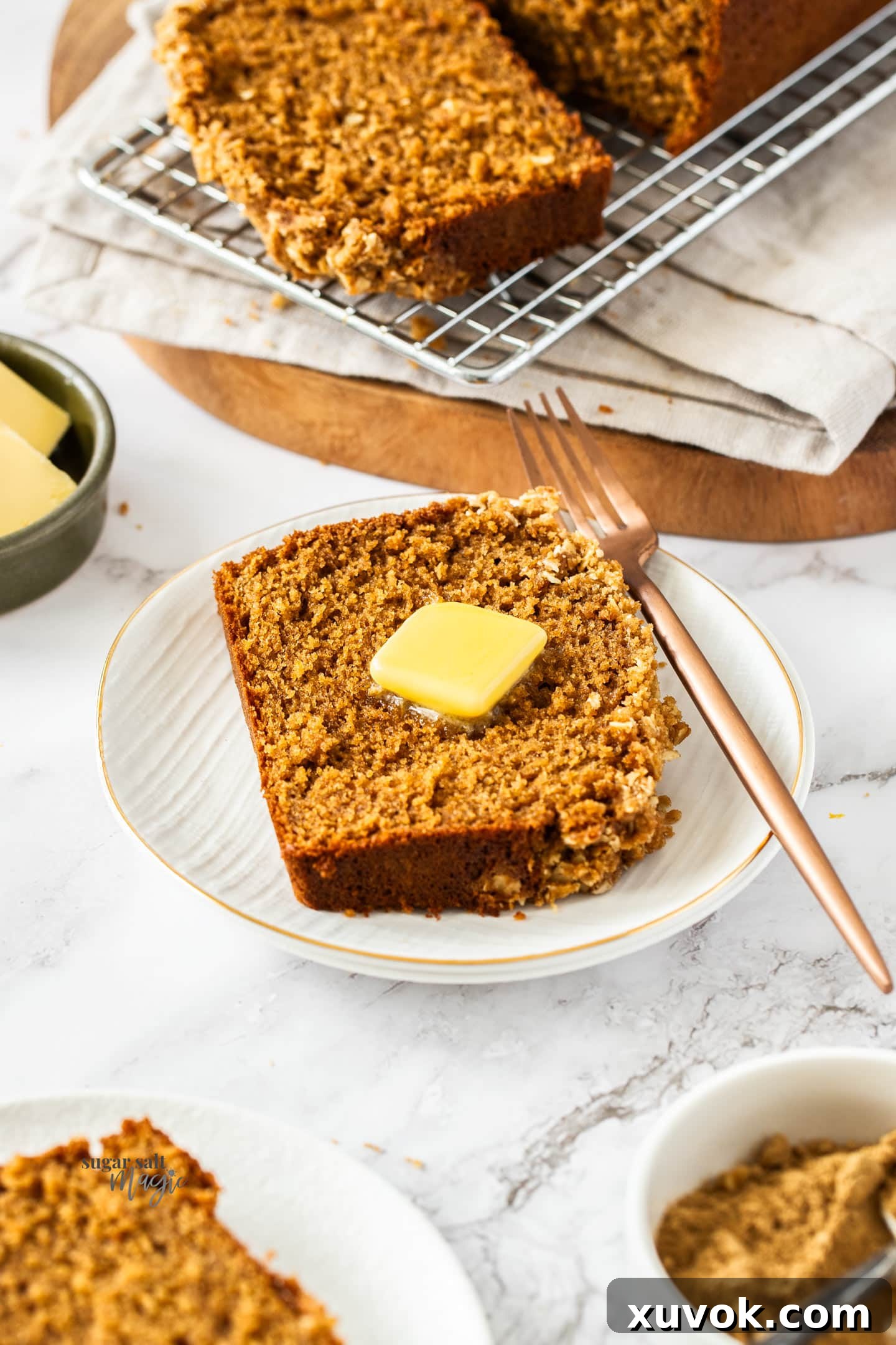 A slice of ginger loaf cake on a dessert plate with a pat of butter on top.