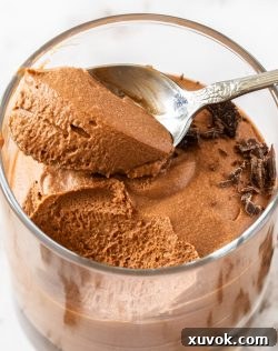 Closeup of the top of a glass of chocolate mouse with a spoonful sitting on top.