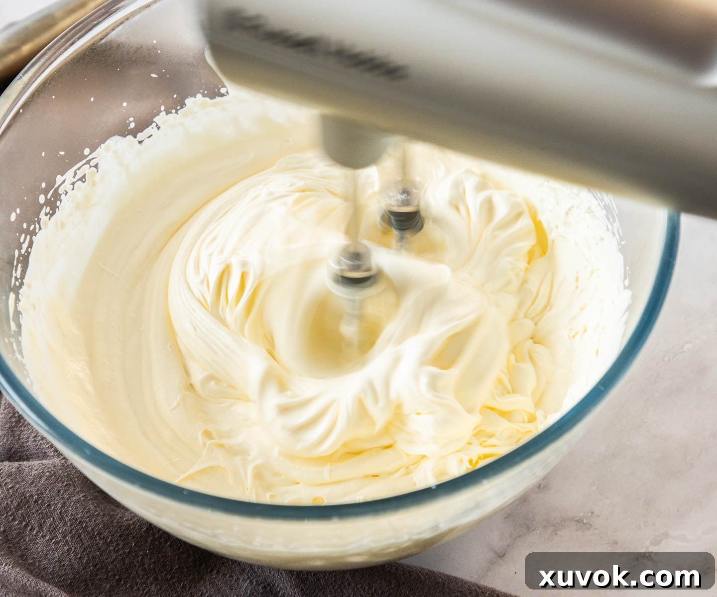 Whipping heavy cream in a bowl with an electric beater.