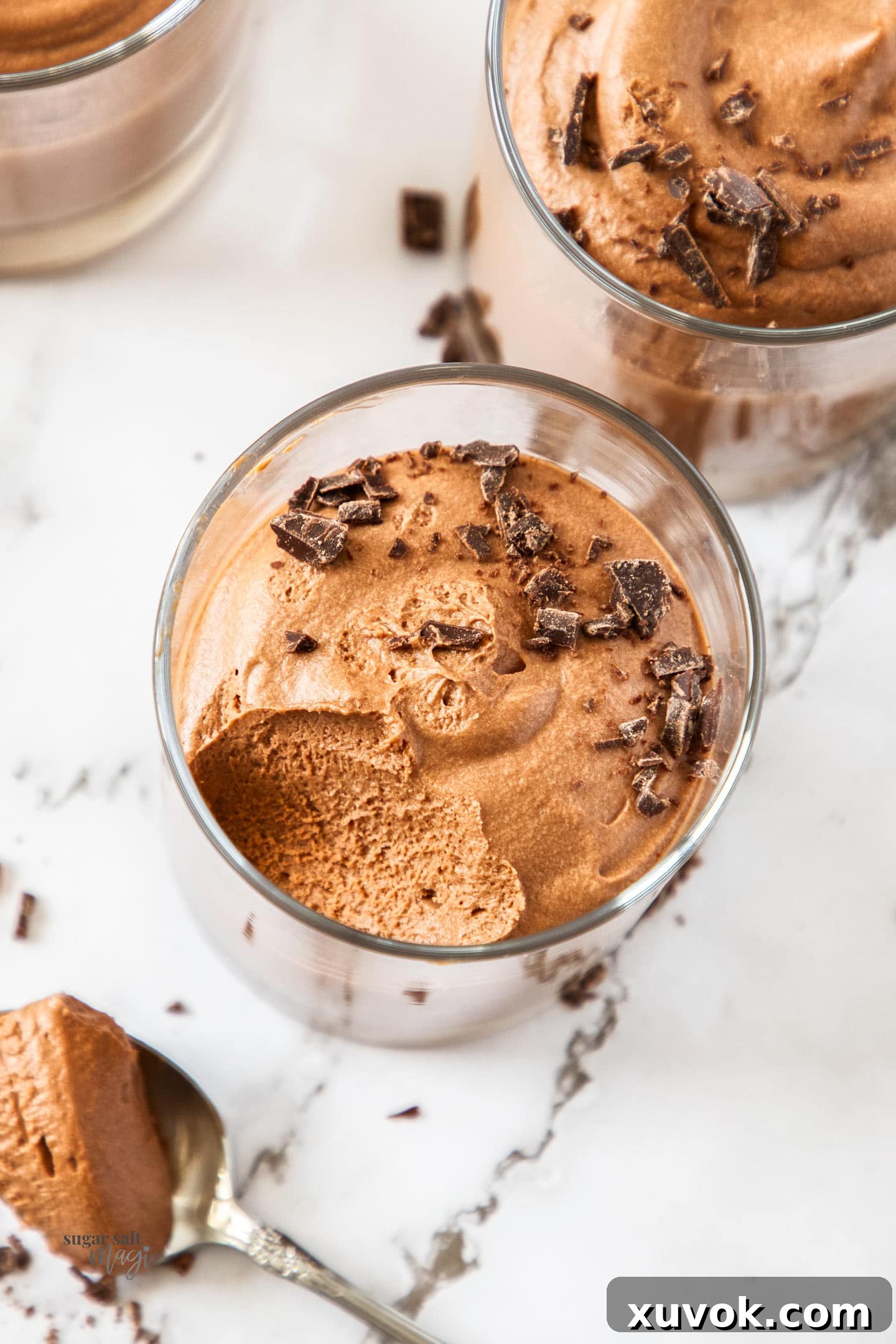 Top down view of a glass of easy chocolate mousse with a scoop removed, garnished with chocolate shavings.