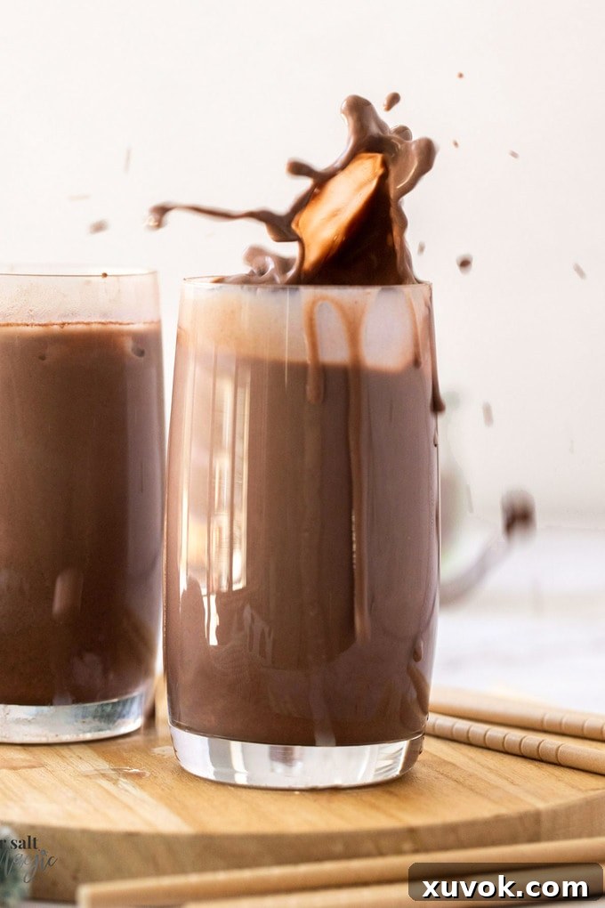 A dynamic shot of a glass of chocolate milk with a splash erupting from the top, emphasizing its refreshing appeal
