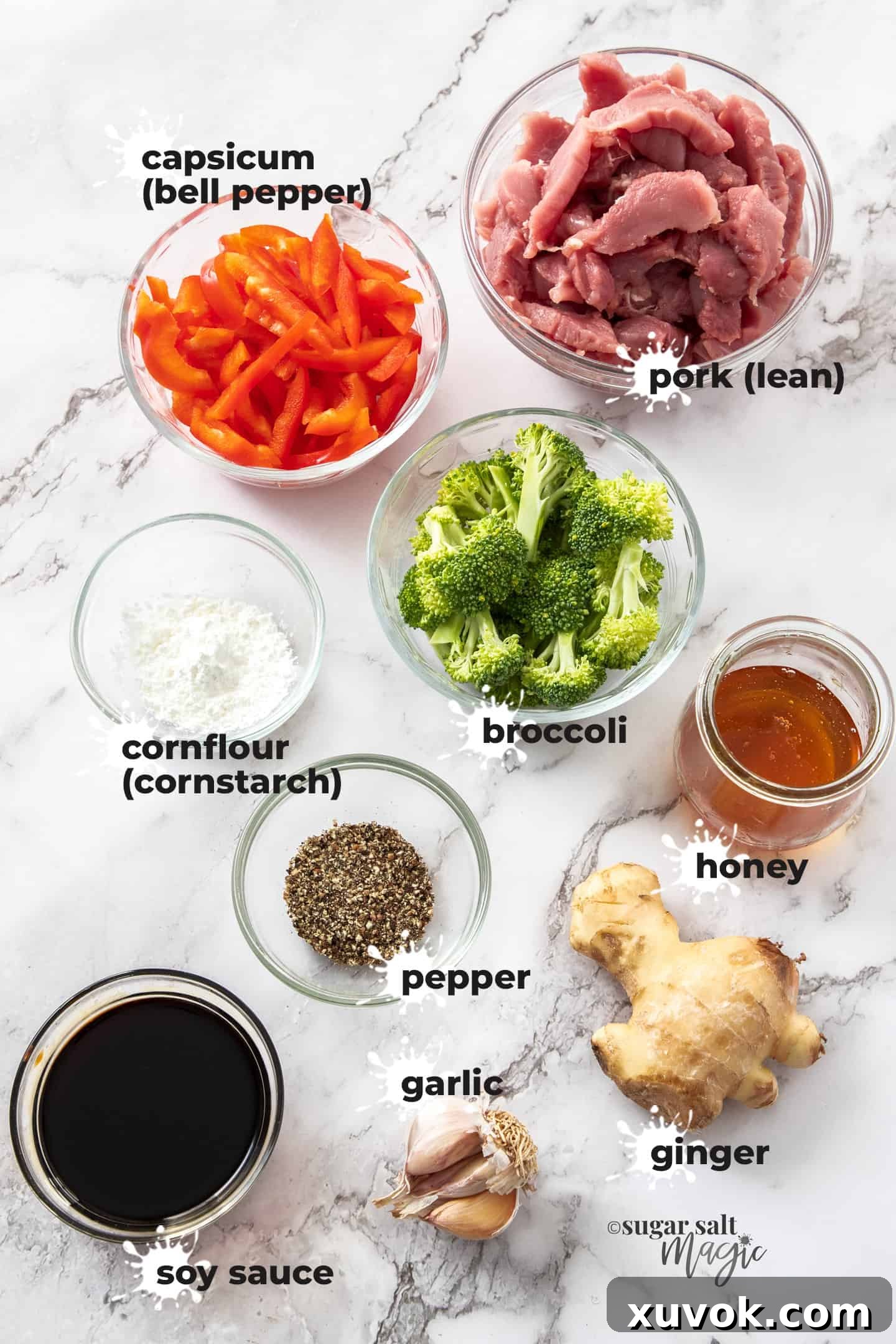 Fresh ingredients for honey pepper pork stir fry laid out beautifully on a marble background, including pork tenderloin, broccoli, red bell pepper, and essential spices.