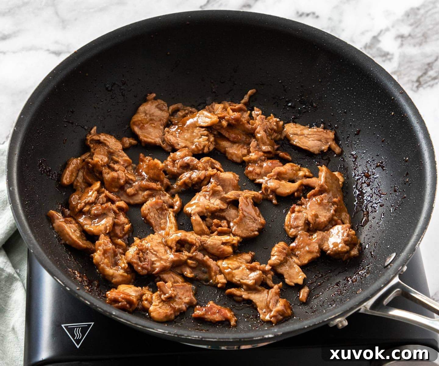 Close-up of beautifully caramelized pork strips in the pan, showing their rich, inviting brown color.