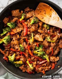Top down view of a pan full of pepper pork stir fry, garnished and ready to serve.