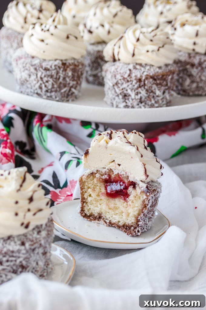 A Lamington cupcake cut in half, revealing the jam filling and the moist cake texture.
