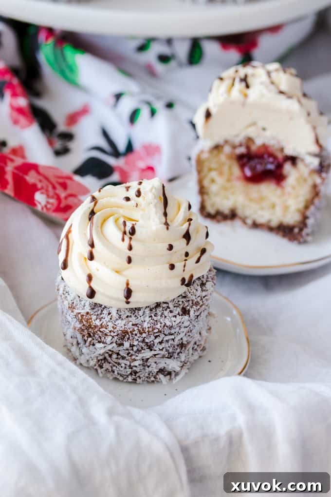 A Lamington cupcake on a dessert plate with another blurred in the background.