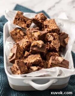 A white casserole dish on a green tea towel, filled with chocolate cereal treats