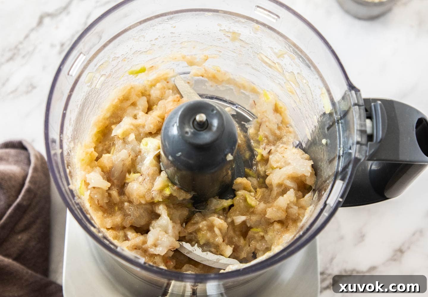 The coarsely blended prawn paste, showing small chunks, inside a food processor bowl.