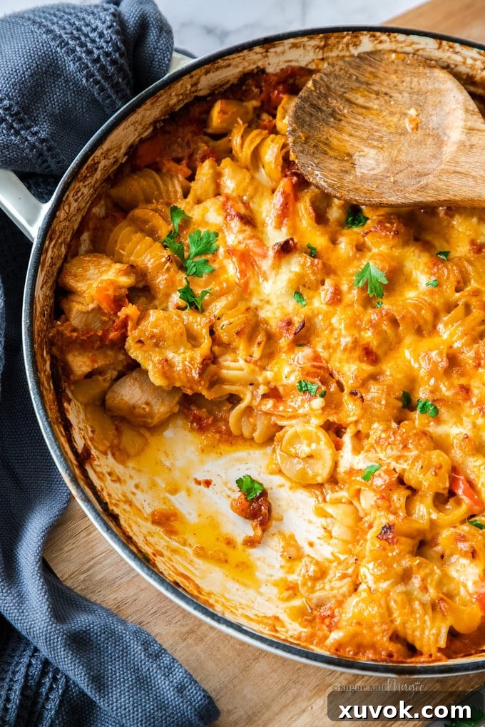 Close up of a pan of pesto pasta bake with a scoop already removed. 