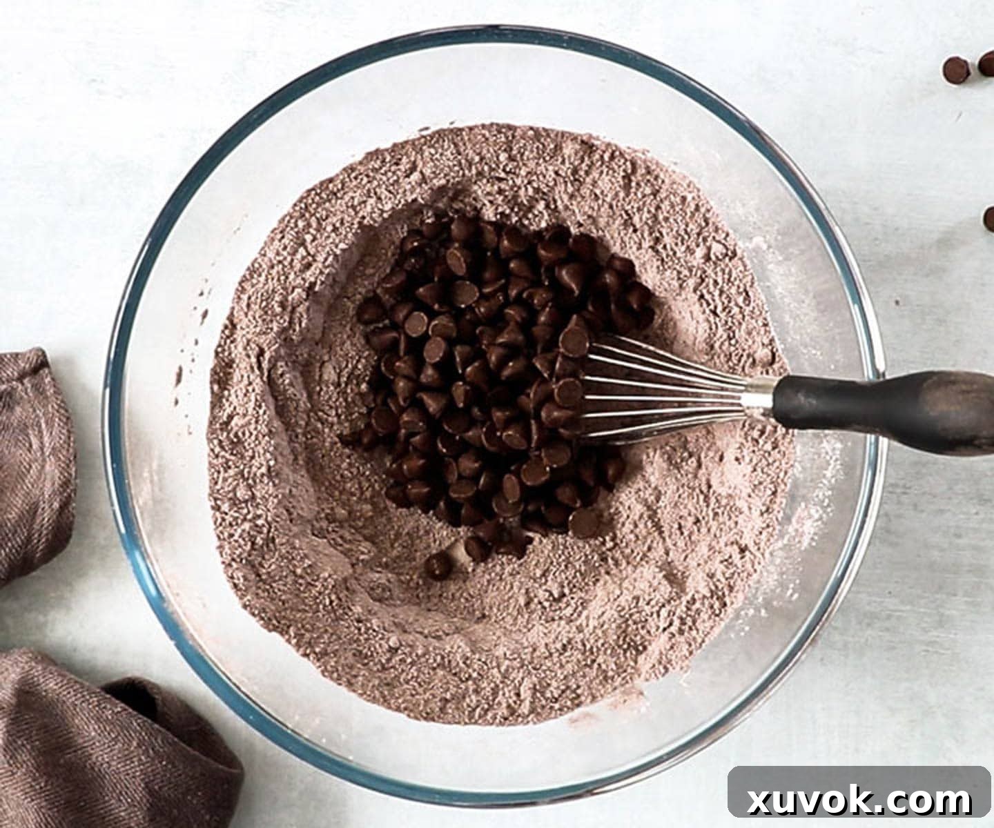 Chocolate chips on top of the dry ingredients in a mixing bowl, ready to be combined for the chocolate bread recipe.