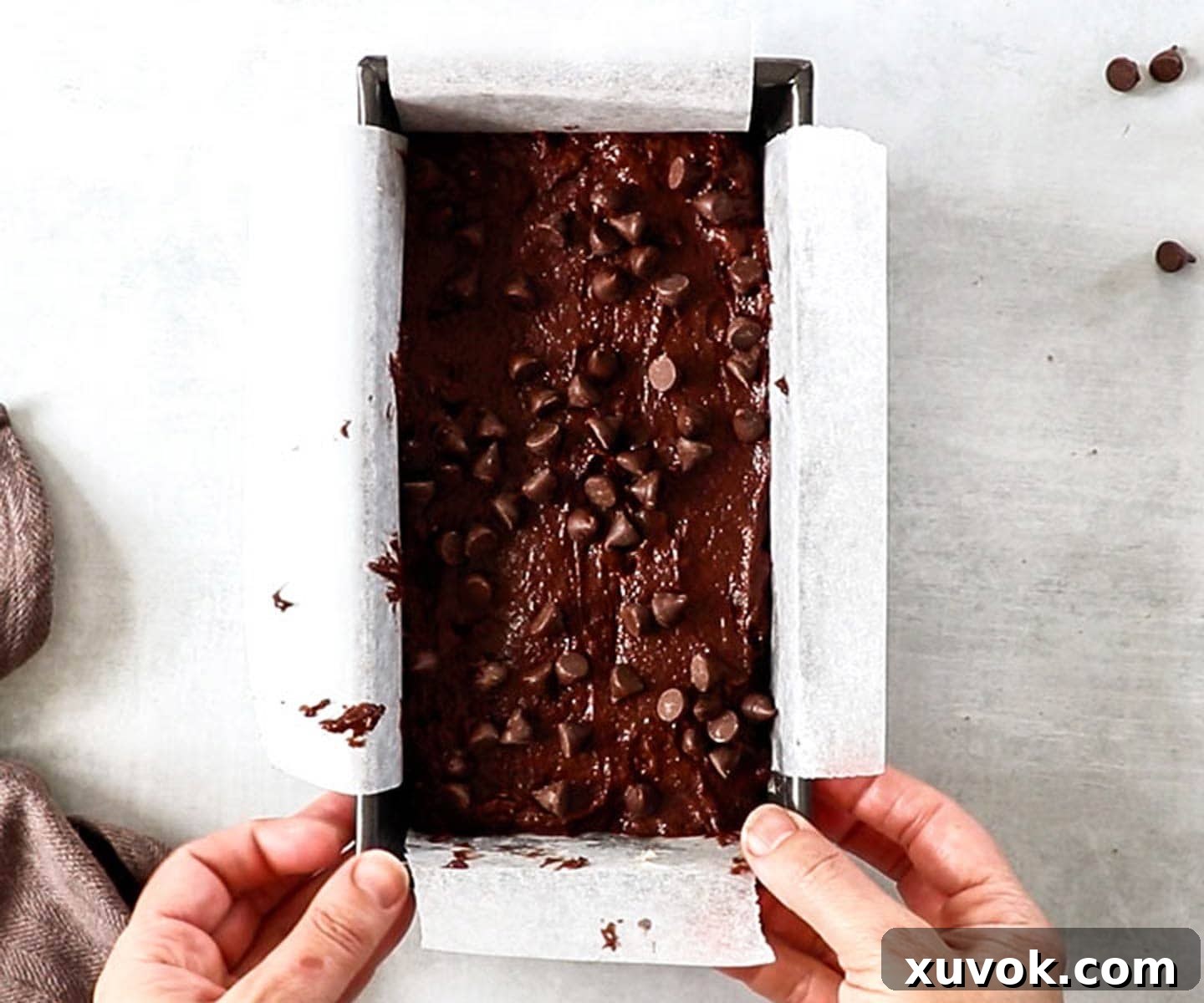The chocolate cake batter topped with chocolate chips in a loaf pan, ready for baking.