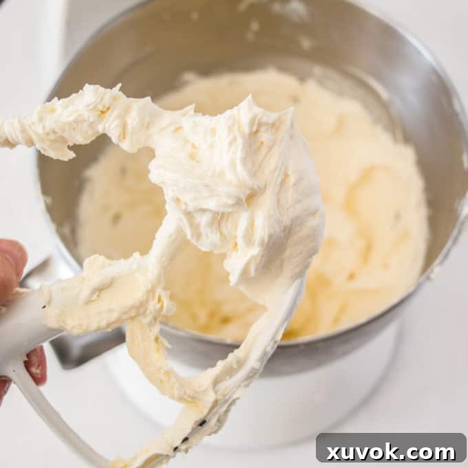 A stand mixer paddle coated in beautifully whipped white Ermine buttercream, showcasing its light and airy texture.